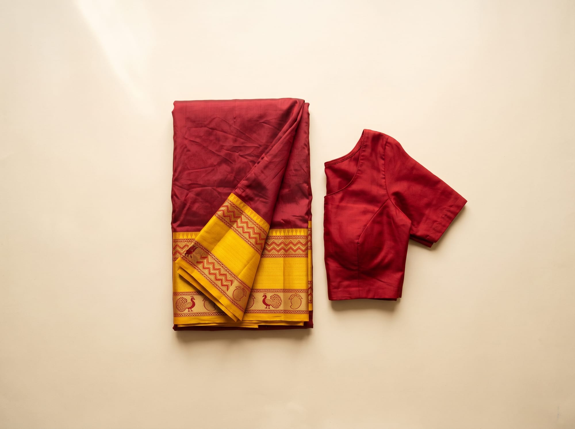 Flat lay of a red Molakalmuru silk saree with a woven yellow border and a plain red blouse.